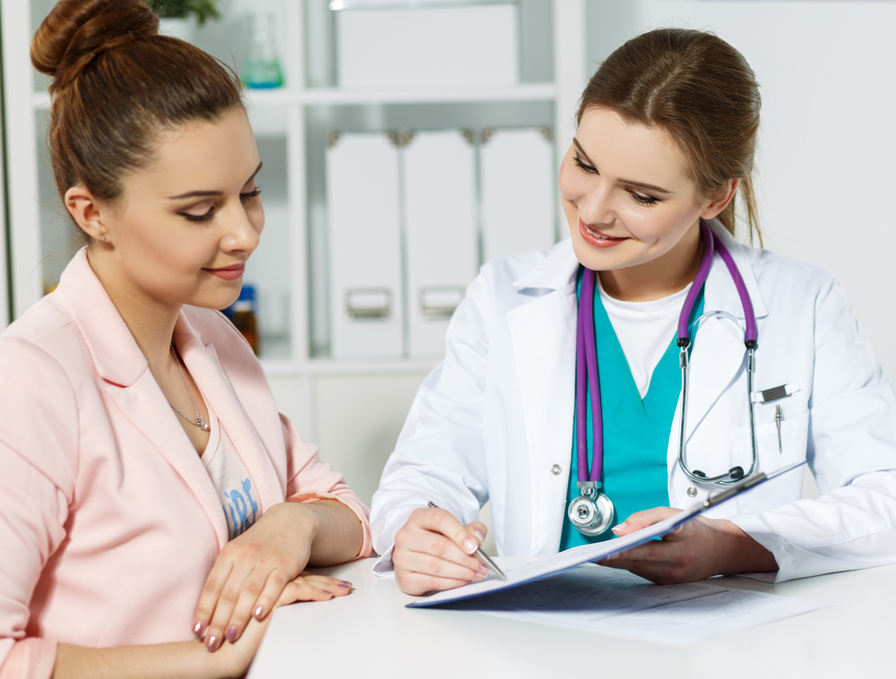 femeie discuta cu un medic care ii indica ceva pe un clipboard
