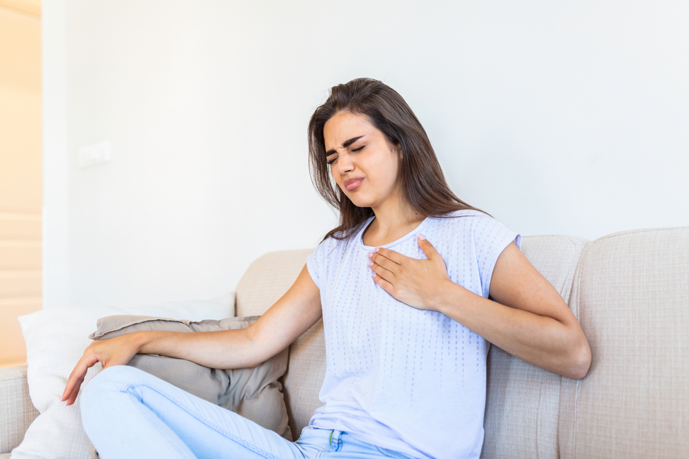 Femeie tinandu-si mana pe piept indicand durerea